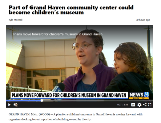 Woman holds child, being interviewed in front of Grand Haven's Central Park Place building.